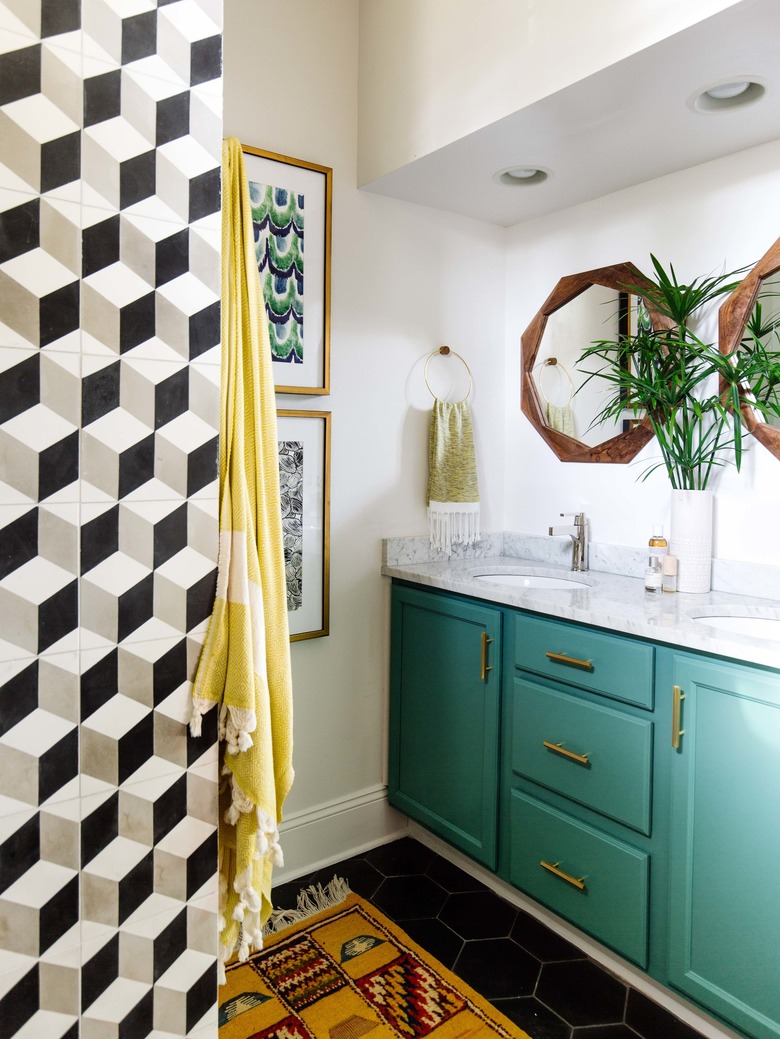 small midcentury modern bathroom with green cabinets and black and white tiled wall