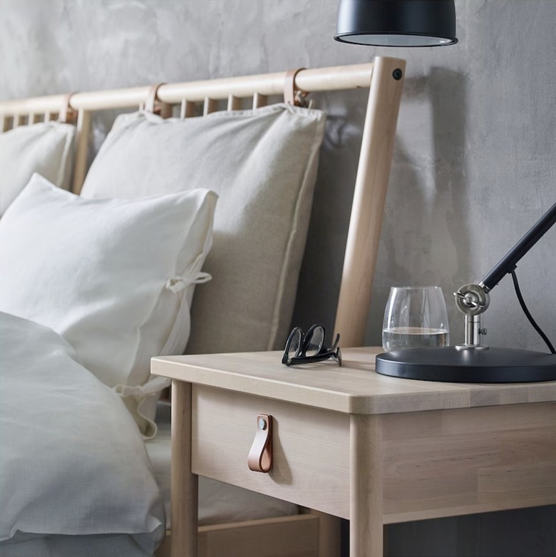 wood nightstand with leather pull in front of bed