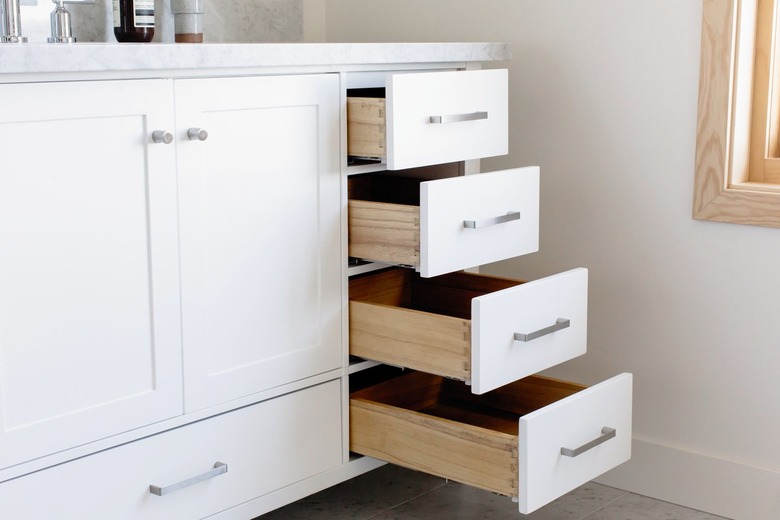 A white bathroom vanity with drawers of varying sizes. The smallest drawers are open at varying degrees.