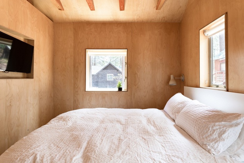 small spaces minimalist wood-walled bedroom with small windows and white bedding