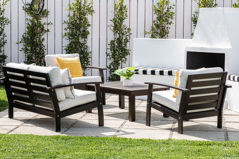 small spaces with Brown frame patio furniture with white cushions and yellow pillows with a fireplace