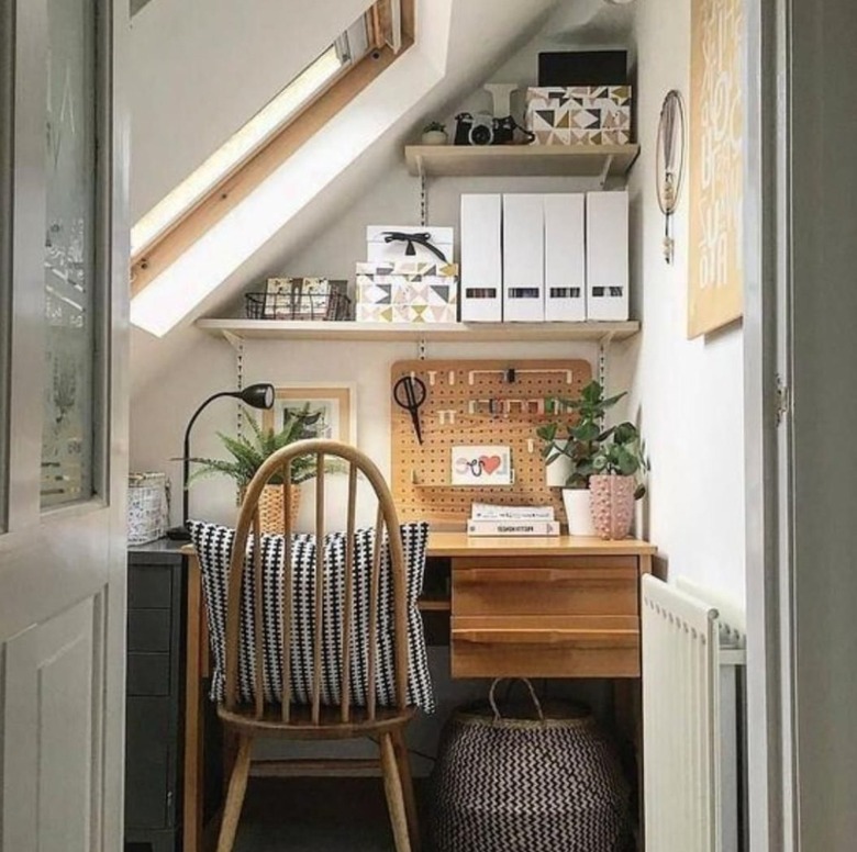 Home office set up in nook. Shelves, chair, plants, pillow, basket.