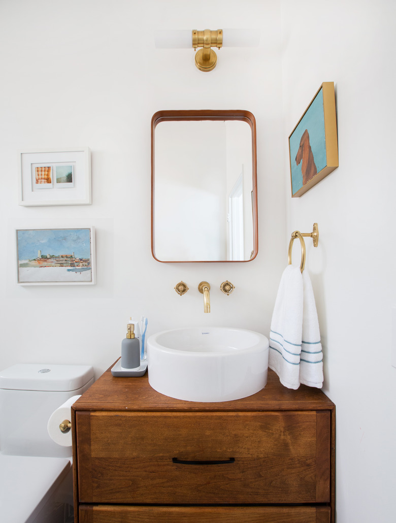 Vessel bathroom sink on wood vanity cabinet with wall-mounted faucet