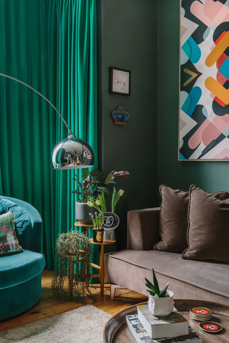 green walls in a living room with a brown couch and arc lamp