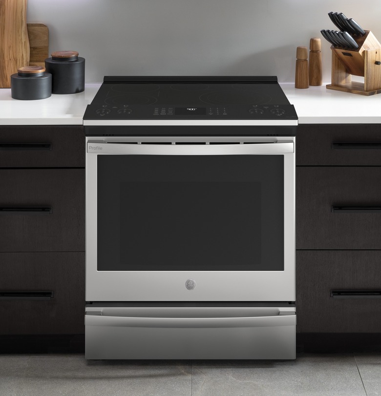 Kitchen with stainless steel electric stove, black cabinets, white counters.