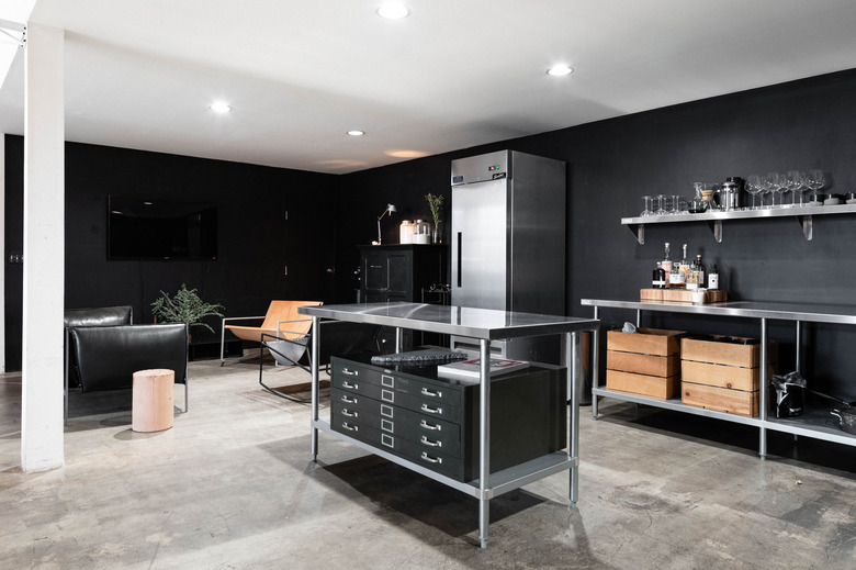 stainless steel kitchen island with black storage bins in black kitchen