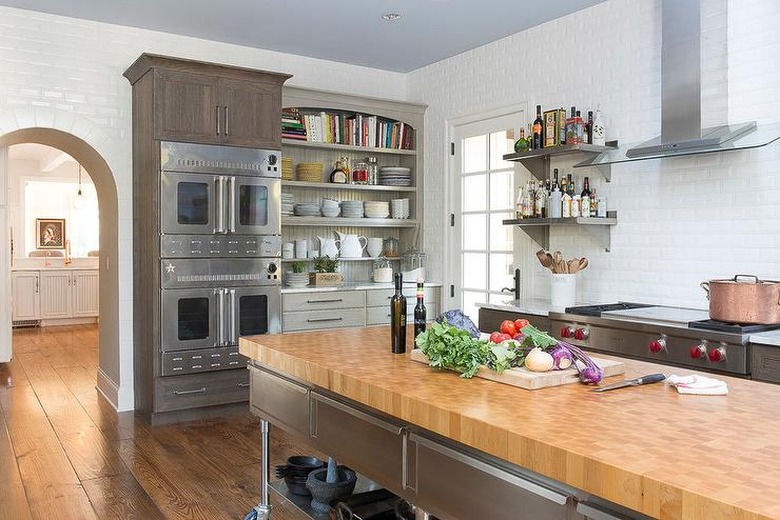 stainless steel kitchen island with butcher block counter in kitchen with double ovens