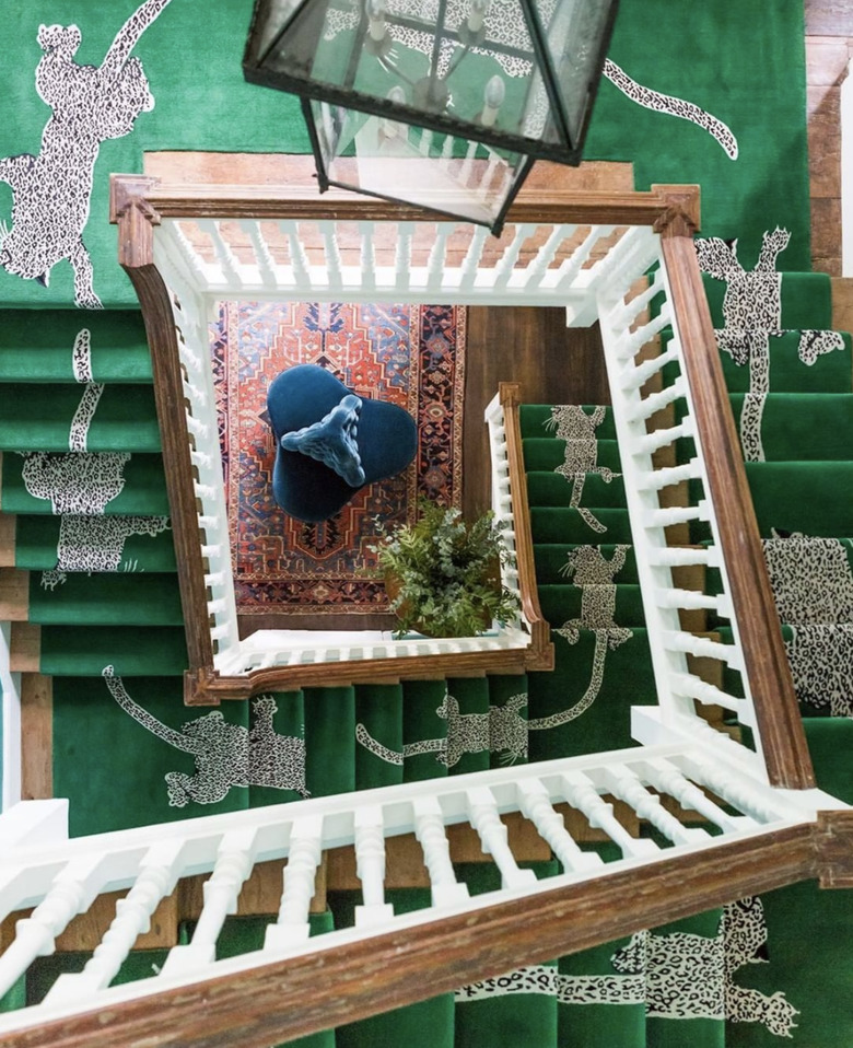 green and leopard-print stair runners on spiral staircase with wood railings