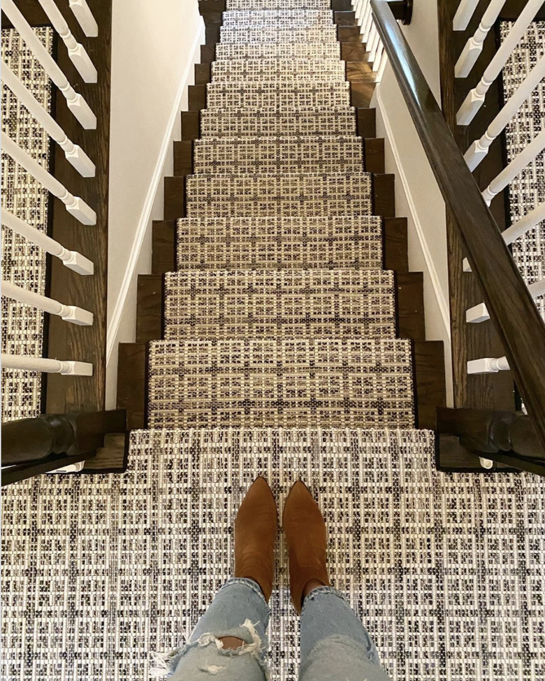 Woven stair runners on dark wood stairs with white spindles