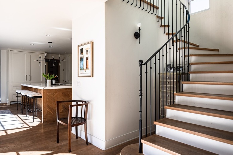 A wood stepped staircase idea with black railings in a white-walled house