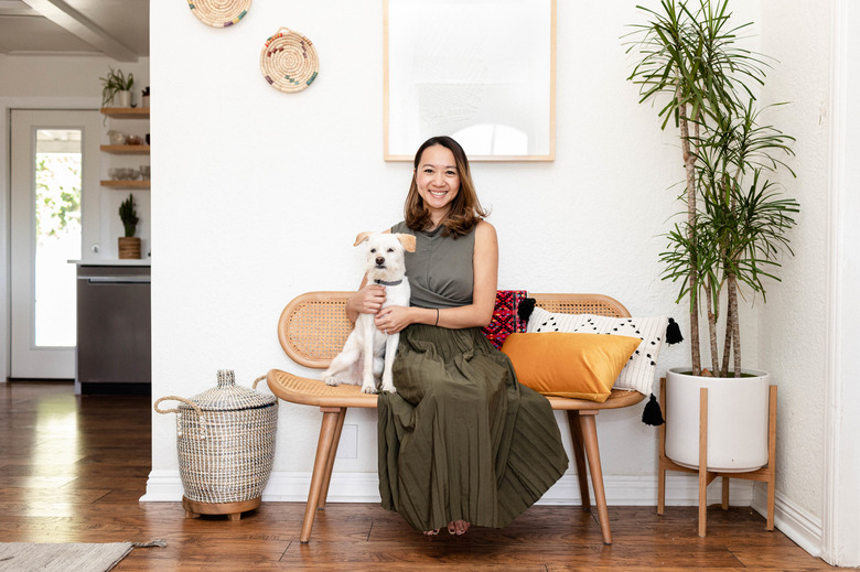 woman with dog sitting on bench with plant nearby