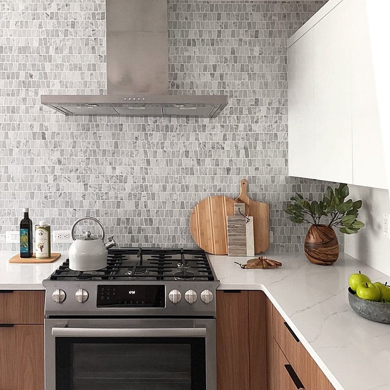 marble mosaic kitchen backplash with wood cabinets and marble countertops exposed hood