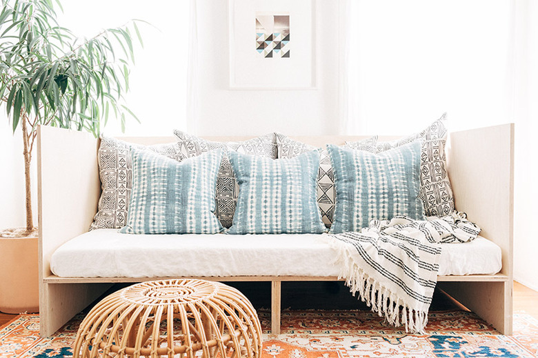 studio bedroom idea with plywood daybed, a twin mattress, and blue and gray throw pillows