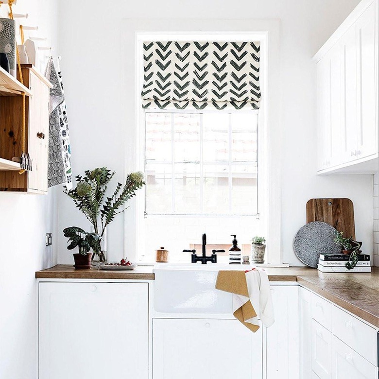 white kitchen with butcher block countertops and patterned roman shade