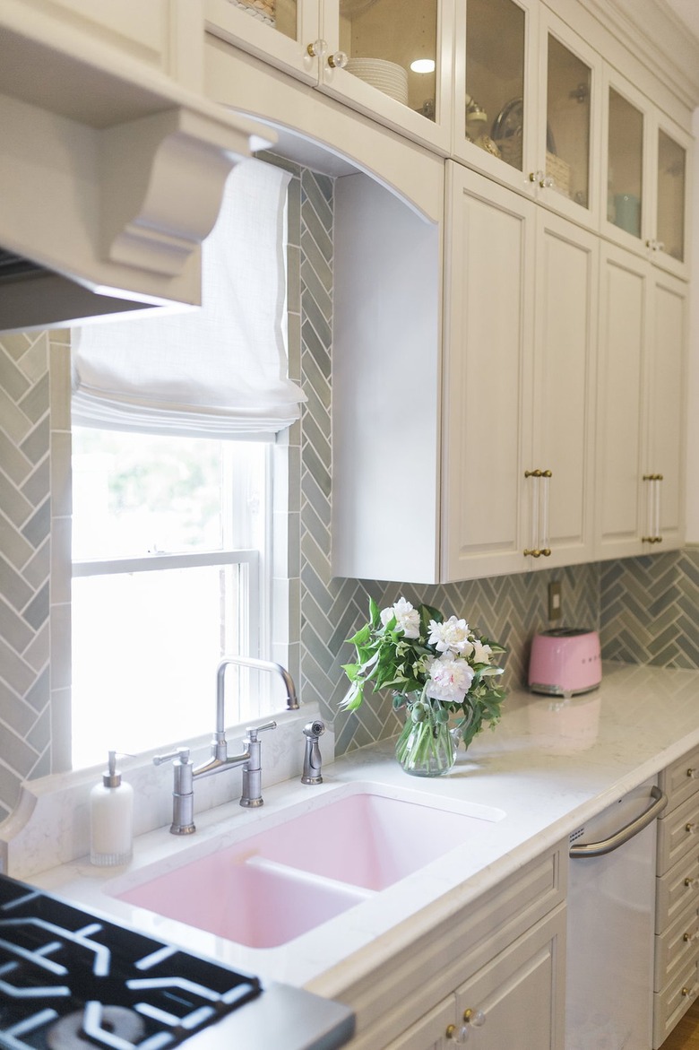 light green herringbone subway tile backsplash with pink sink