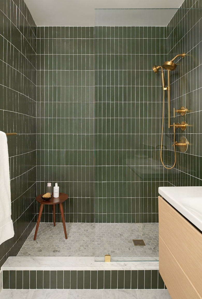 vertical green subway tile shower idea with gold fixtures