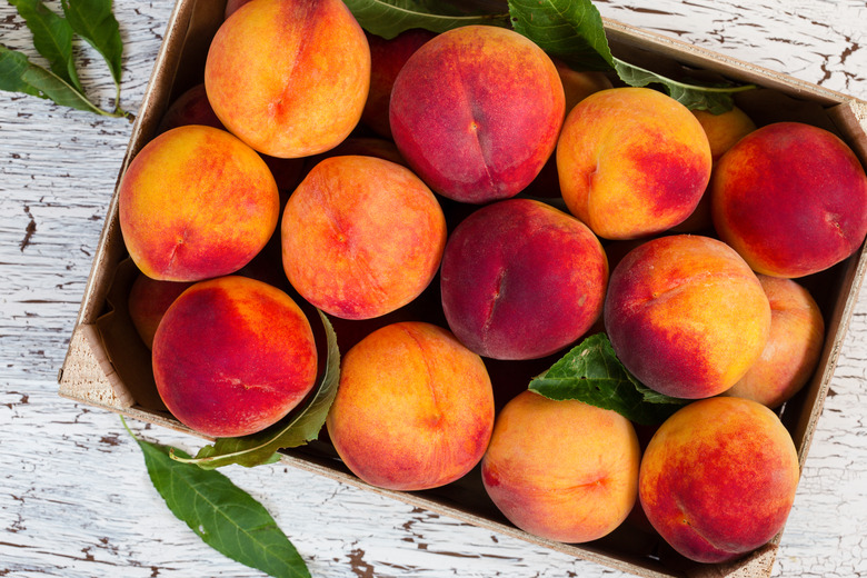 Fresh organic peaches in wooden crate.