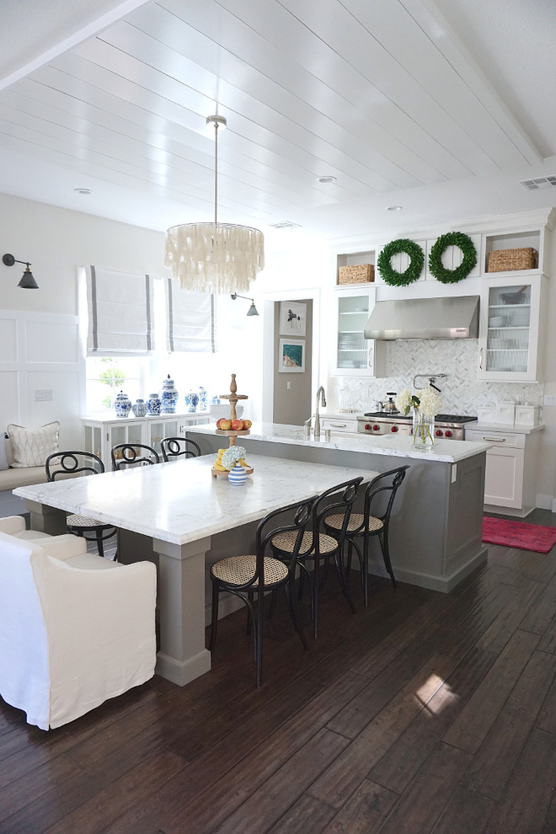 T-shaped kitchen island with a variety of chairs and chandelier in farmhouse kitchen