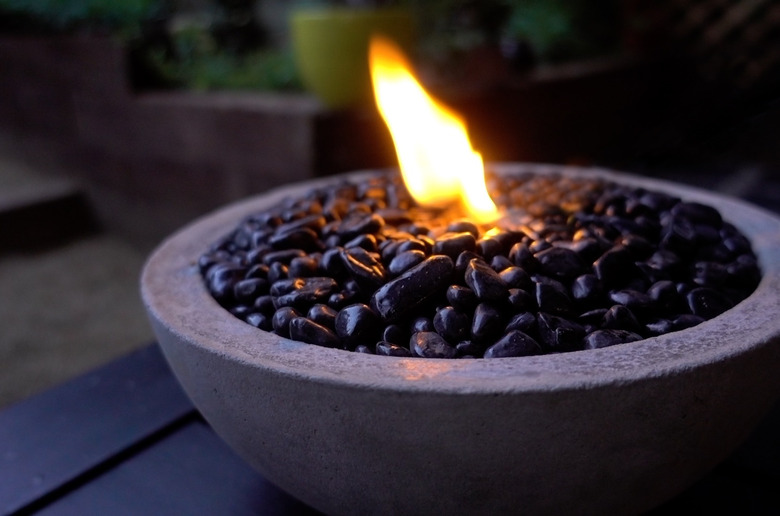 DIY tabletop concrete fire bowl on an outdoor coffee table in the evening.