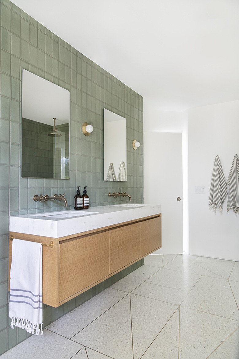 two wide vanity mirrors on green tiled bathroom