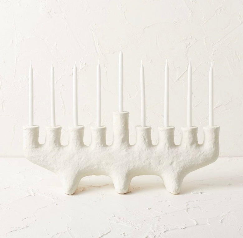 A white, carved clay menorah, with nine white candles.