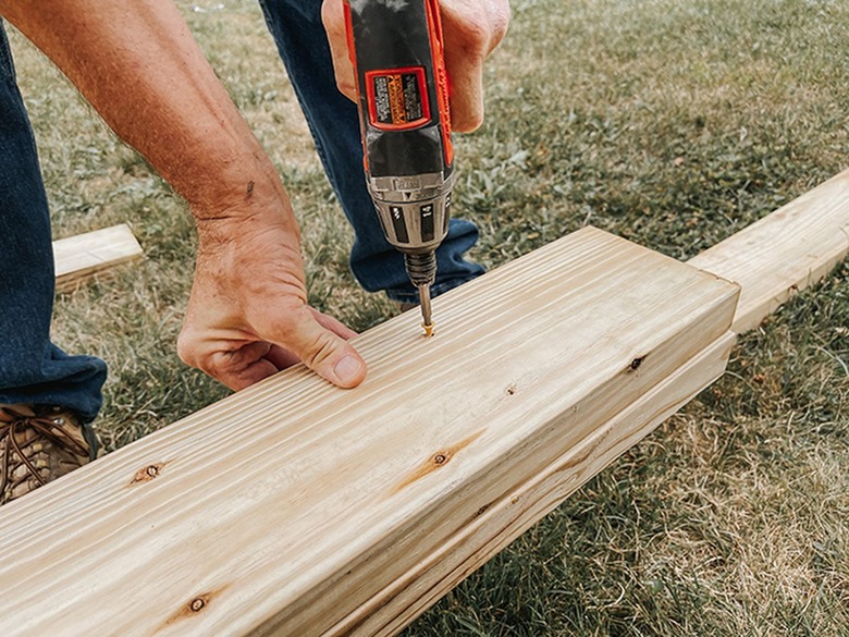 A construction worker drilling holes into wood boards