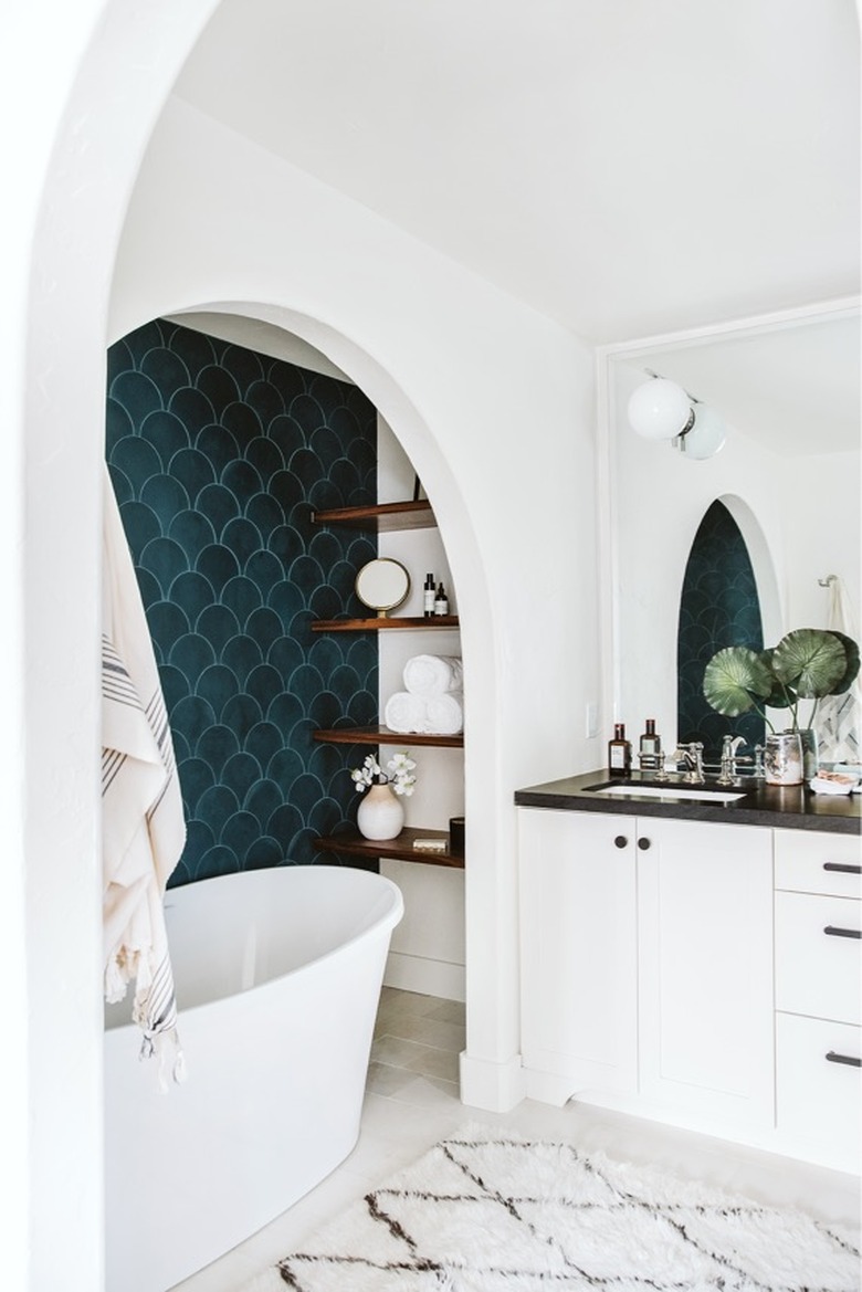 white bathroom with teal color scallop wall tile with freestanding tub