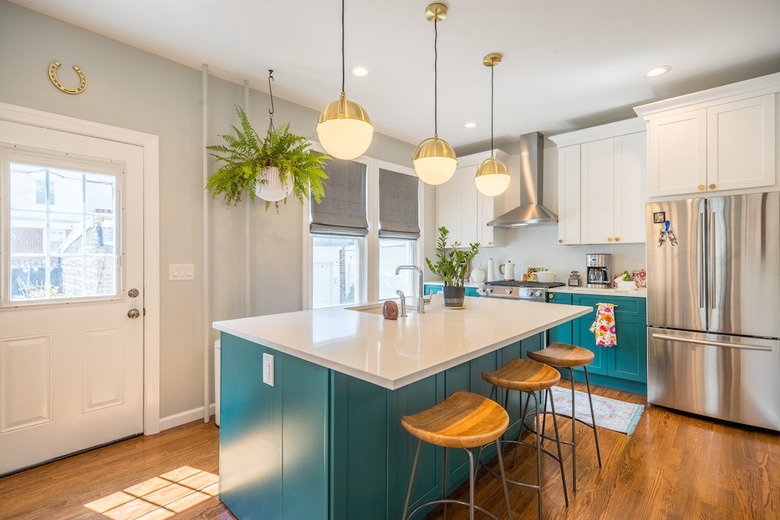 bright teal kitchen island with brass pendant lighting