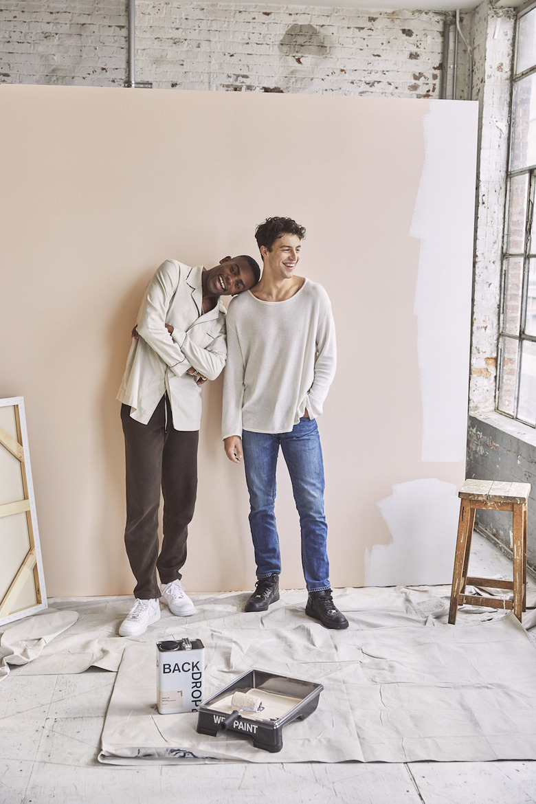 two figures in front of a partially painted wall