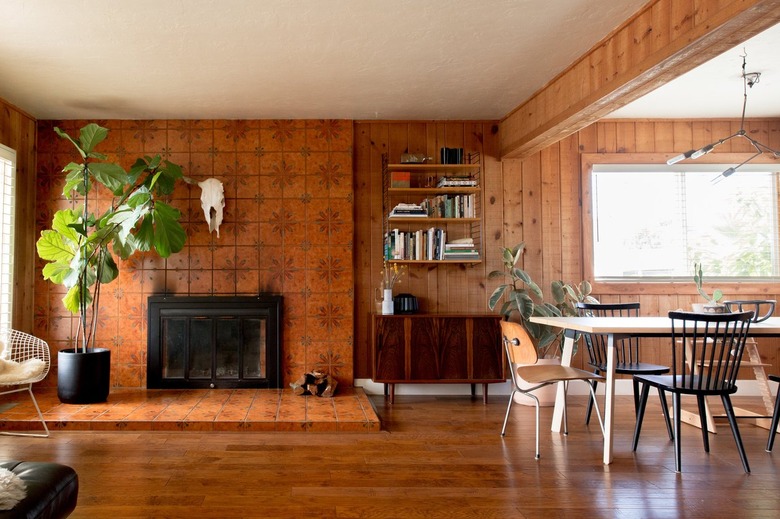 Southwest living room with animal skull, brown floral fireplace, wood panel walls, wood bookshelves and eclectic furniture