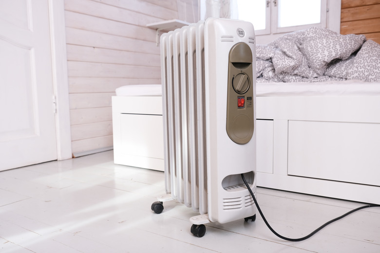 Oil-filled electrical mobile radiator heater for home heating and comfort control in the room in a wooden country house