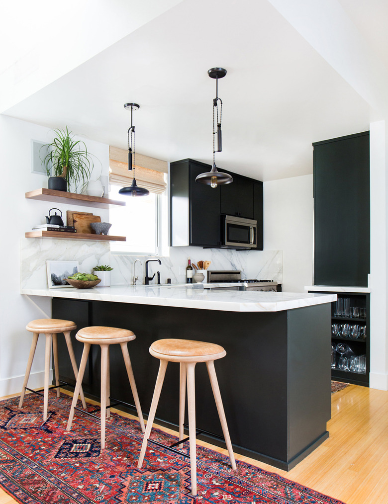 Black bohemian kitchen lighting over white marble countertop with black cabinets