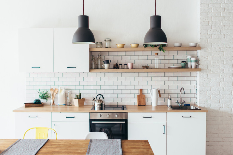 Modern new light interior of kitchen with white furniture and dining table.