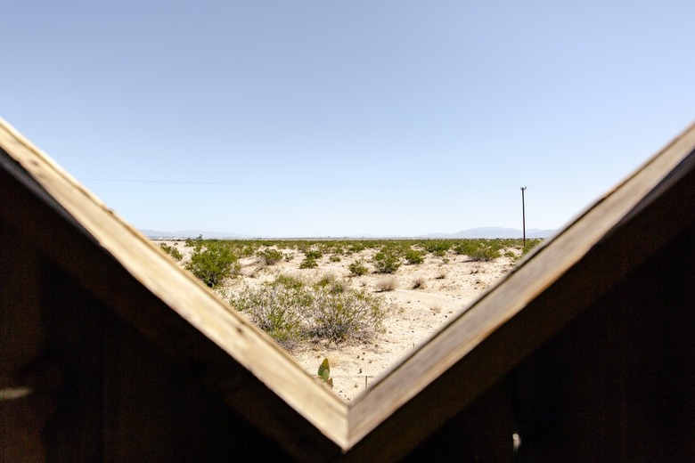 the scrubby, sandy desert as seen through a triangular space in the dining structure's wall