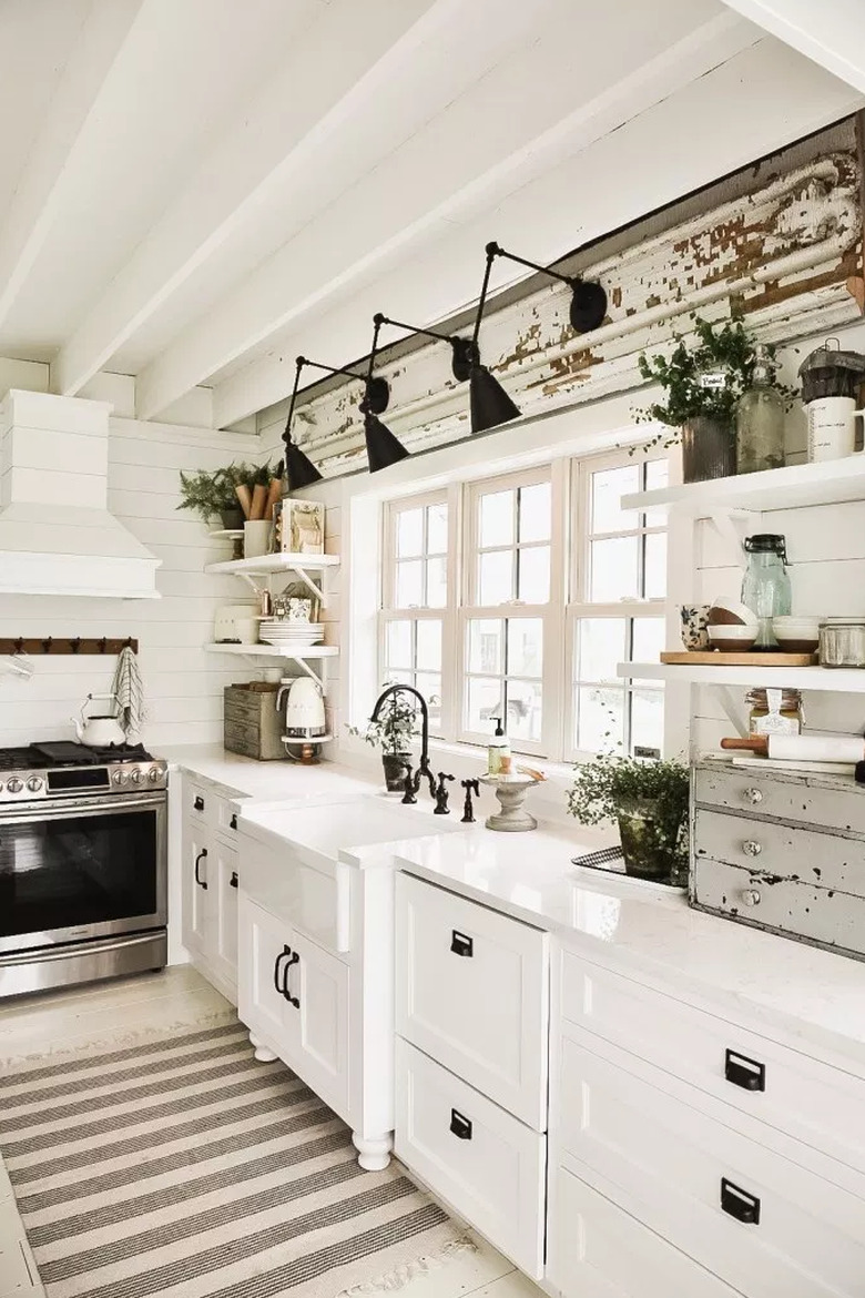 Farmhouse kitchen lighting with black wall sconces above apron sink