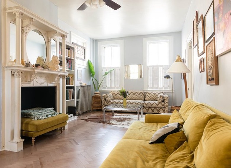 psychedelic grandma apartment with ornate fireplace and mustard yellow velvet couch