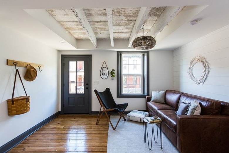 modern farmhouse living room entryway with brown leather couch and rattan pendant lamp