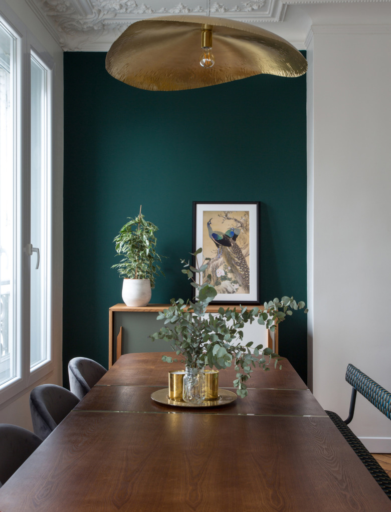 green dining room in Paris apartment with mismatched chairs and modern chandelier