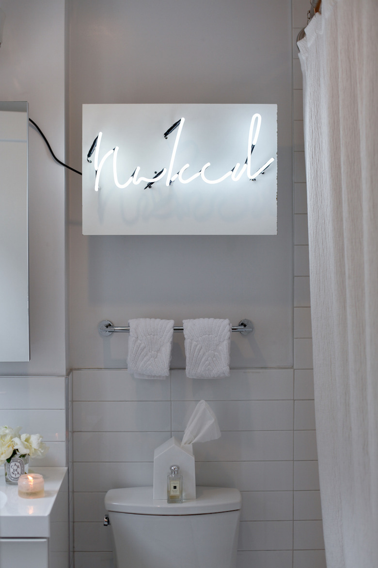 neon sign in all white bathroom