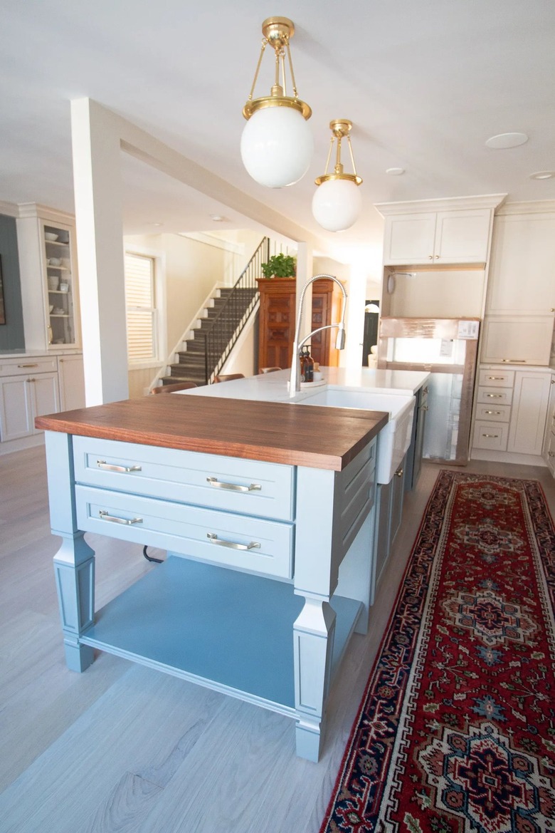 blue butcher block at end of white island in modern kitchen