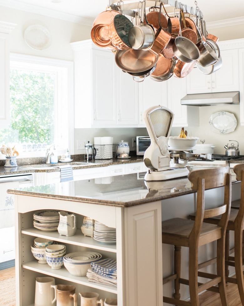 vintage servingware displayed on shelf at end of kitchen island