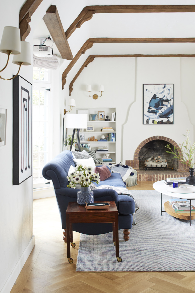 Built-in living room shelving idea near brick fireplace and exposed beams