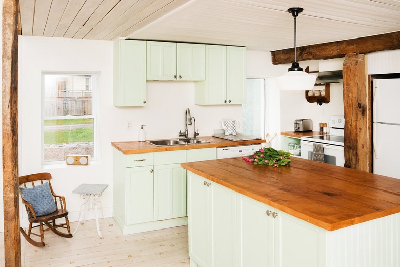 a half-timbered kitchen with a wooden ceiling, a pine-topped island, wood floors, green cabinets, and a wooden ceiling