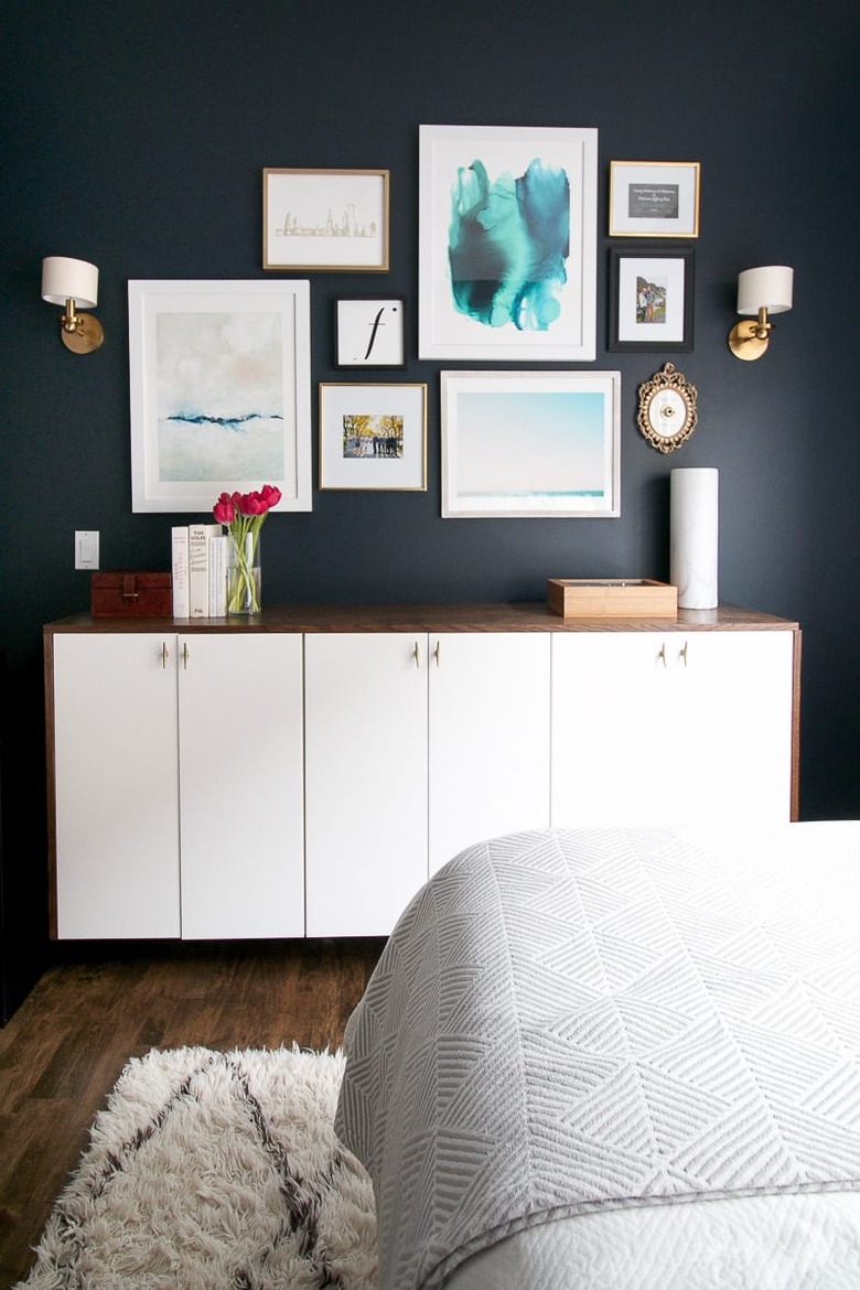 dark blue guest bedroom decorating idea with framed artwork above cabinet