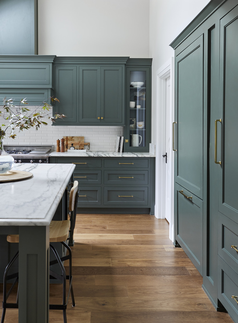 green kitchen cabinets with marble countertops and wood flooring