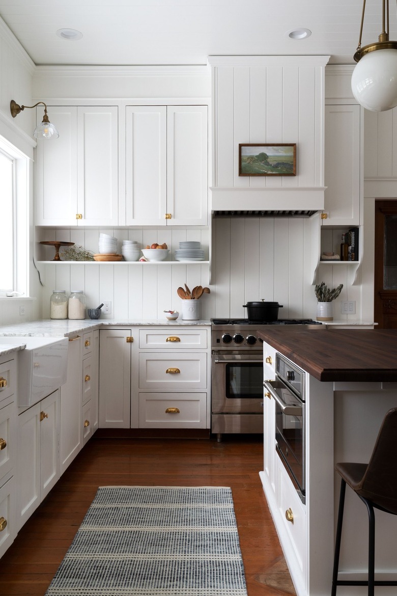 white farmhouse kitchen with white cabinets and oil painting