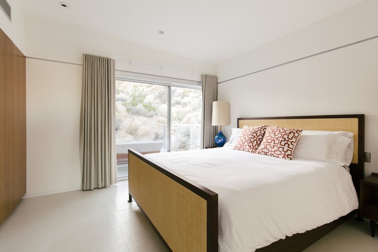 a bed with asian-patterned pillows in a light-filled bedroom with a sliding glass door