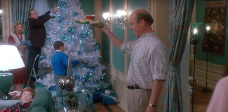 man holding plate of shrimp in apartment decorated with christmas tree, still image from home alone