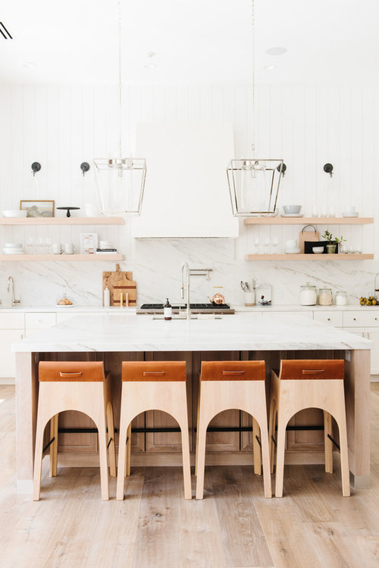 White kitchen design with floating wood shelving and bar stools