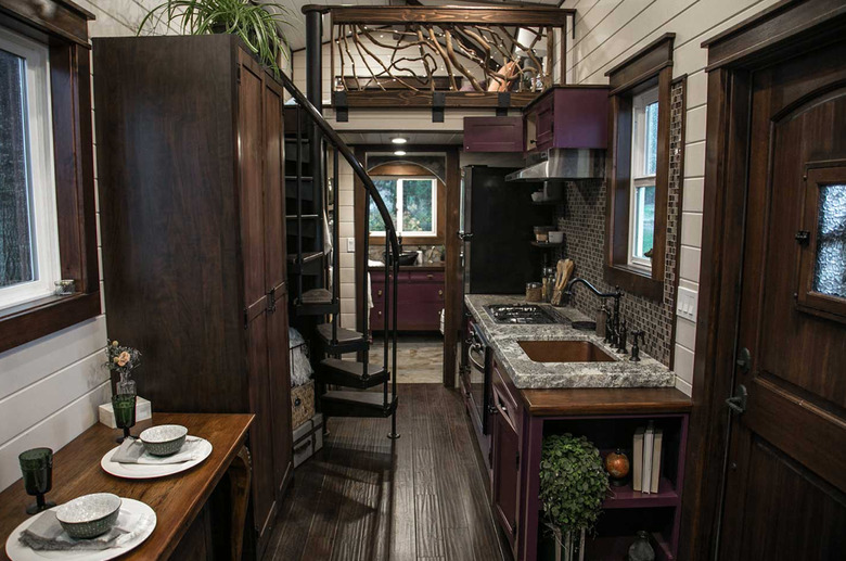 spiral tiny house stairs in home with dark wood floors, and cabinets